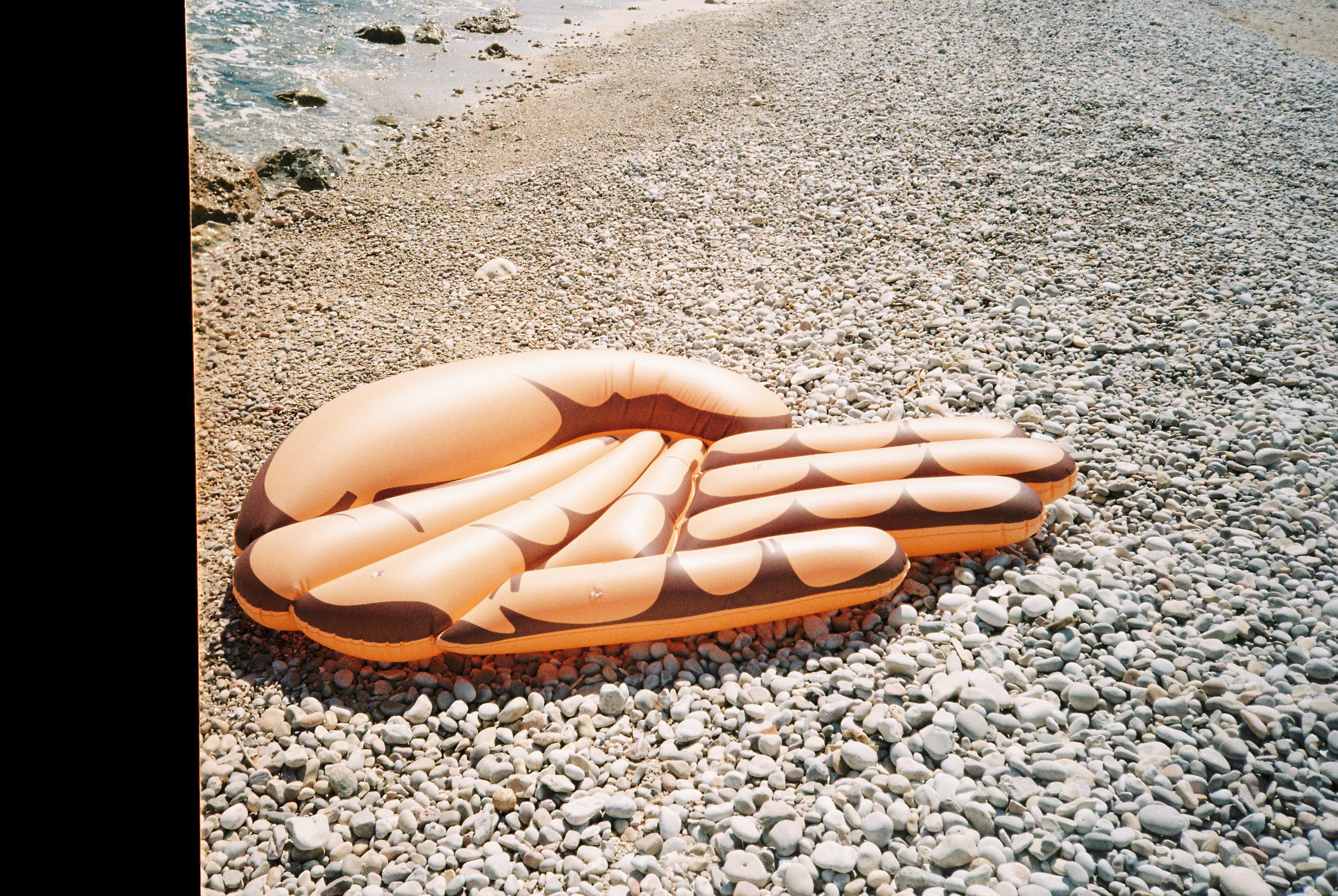 mano gigante flotador toi en la playa